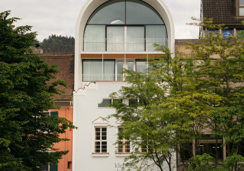Außenansicht des Hotels kleiner Löwe in Bregenz am Kornmarktplatz, gesäumt von Bäumen.