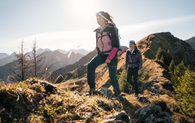Zwei Frauen wandern in der herbstlichen Bergwelt des Kleinwalsertals.