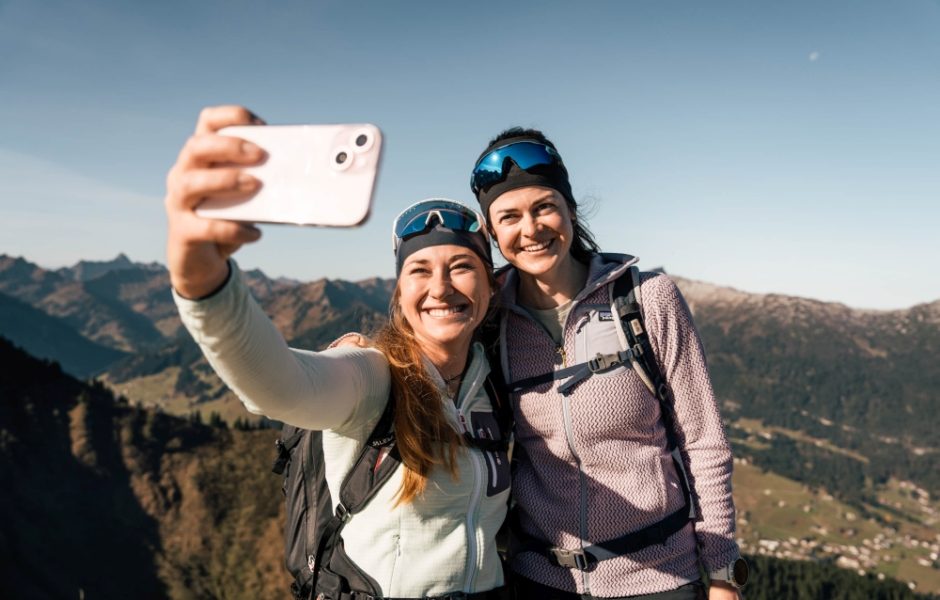 Zwei Frauen machen einen Selfie auf einer Wanderung in den Bergen.
