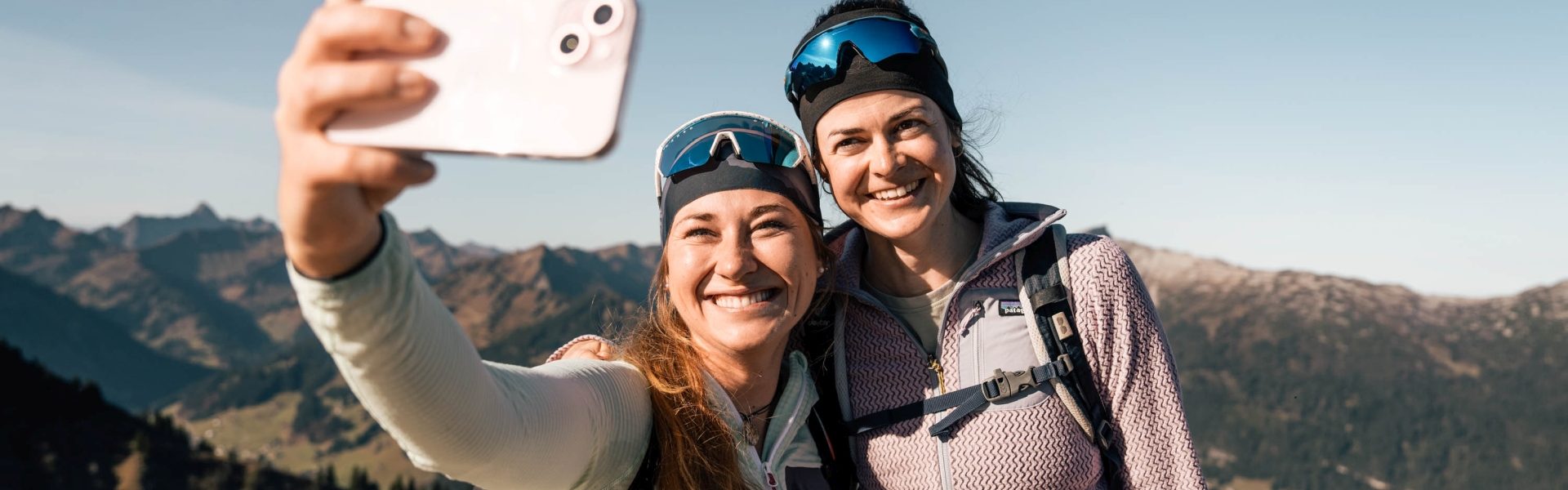Zwei Frauen machen einen Selfie auf einer Wanderung in den Bergen.