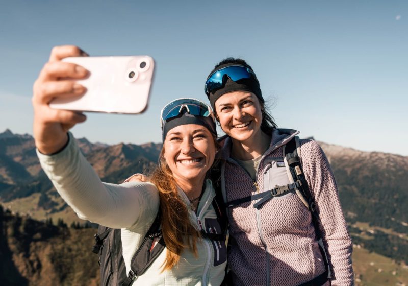 Zwei Frauen machen einen Selfie auf einer Wanderung in den Bergen.